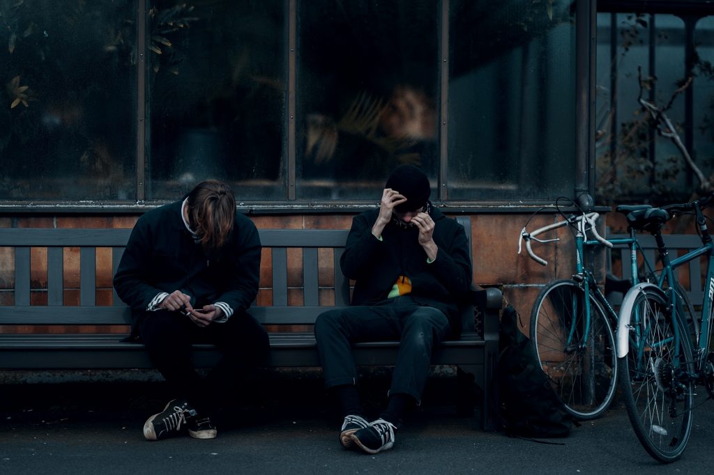 Two teenagers sat on a bench smoking
