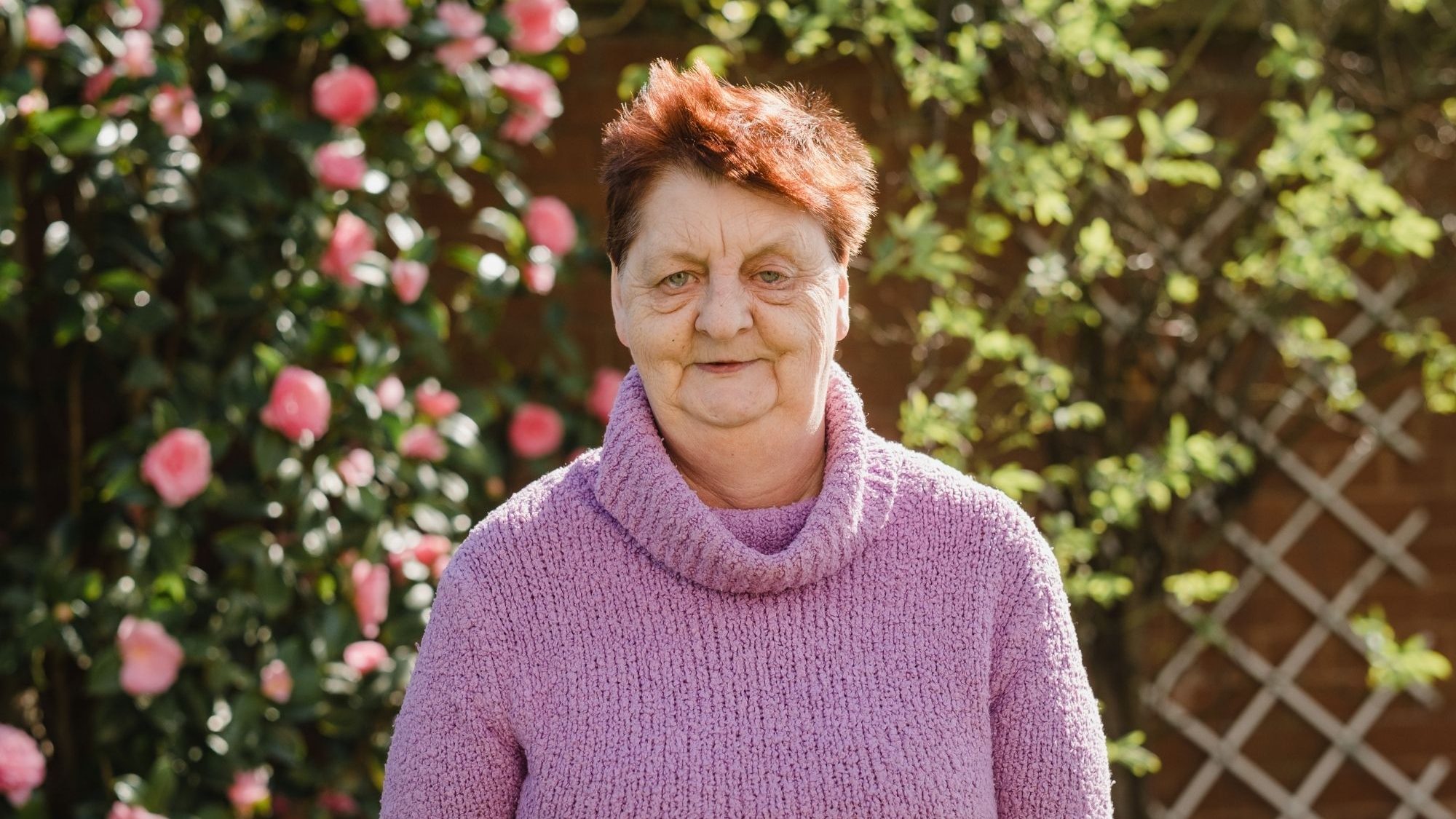 Former smoker Heather Kennedy standing outside smiling in front of a wall of flowers