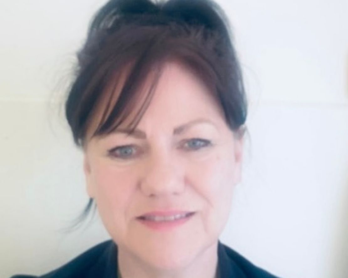 Selfie-style close up photo of CURE nurse Helen Huddart wearing her dark blue nurse uniform and green CURE lanyard.