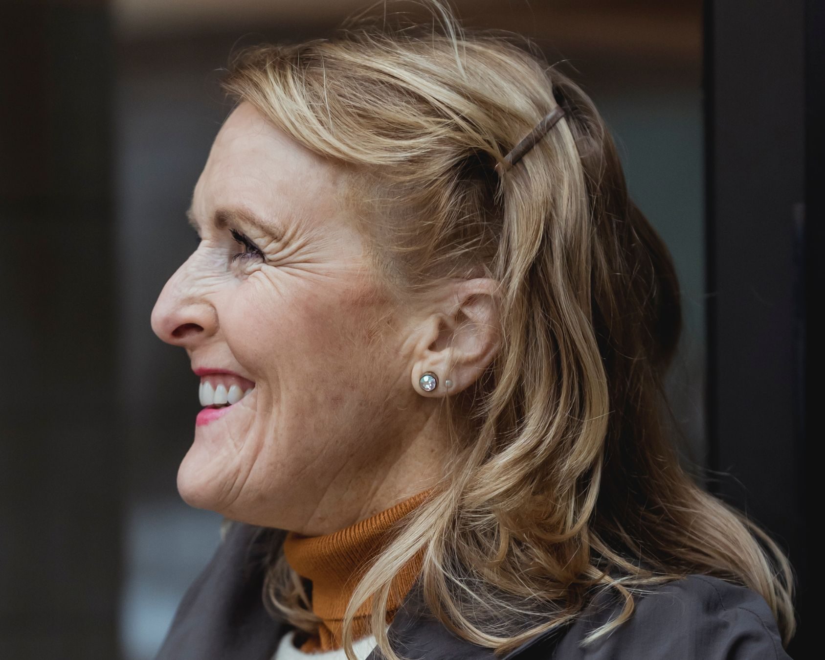Blonde woman looking to the left with a toothy smile