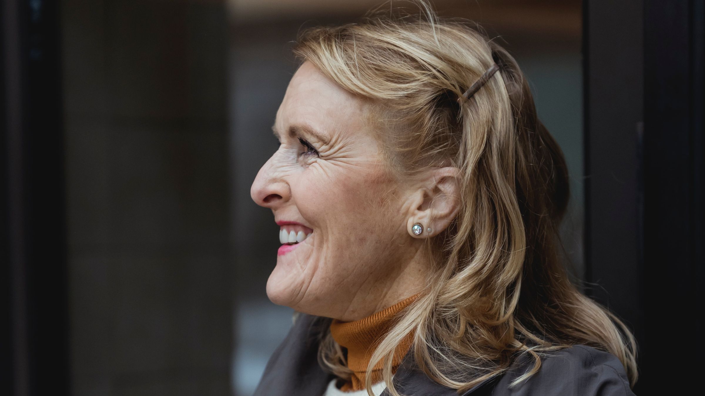 Blonde woman looking to the left with a toothy smile