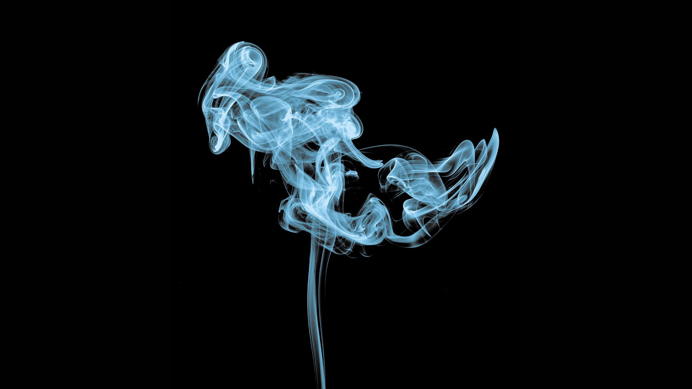 Cigarette smoke rising up against a black backdrop.